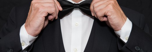 Close-up of a gentleman wearing Black Tie straightens his bowtie.